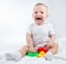 Photo of a crying nine-month-old baby with bright toys