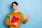 Photo of curious brunet millennial guy hold books look empty space wear brown sweater isolated on blue color background