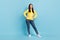 Photo of curious cute lady hands hips look empty space wear yellow jumper jeans shoes isolated blue background