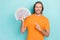 Photo of cute cheerful man wear orange t-shirt pointing finger cash empty space  turquoise color background