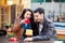 photo of cute couple sitting on the bench and looking at the heart shaped toy on the wonderful cafe background