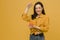 Photo of cute female holds slinky and plays with it. Wears yellow shirt, isolated yellow color background