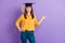 Photo of cute lady direct fingers empty space look camera wear yellow shirt blue pants college cap isolated violet color