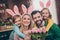 Photo of cute lovely family with bunny ears celebrate easter holiday father hold present for mother bunch of flowers