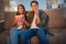 Photo of cute scared young couple wear casual shirts smiling sitting couch watching scary movie eating pop corn indoors