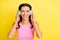 Photo of cute shiny young woman pigtails wear tank top arms earphones empty space isolated yellow color background