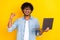 Photo of delighted handsome man hold netbook raise fist success accomplishment isolated on yellow color background