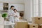 Photo of delighted relaxed husband and wife pose near modern kitchen furniture, have glad expressions, drink takeaway coffee,