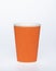 Photo of a disposable orange paper cup on a white background. Photo of a colored coffee cup made of recyclable materials. Empty