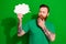 Photo of doubtful unsure guy dressed t-shirt holding speaking bubble arm chin isolated green color background