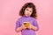 Photo of doubtful unsure little child dressed pullover typing apple samsung device looking empty space  pink