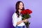 Photo of dreamy affectionate lady smell roses close eyes wear white shirt isolated purple color background