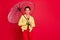Photo of dreamy charming young lady wear yellow jacket smiling walking open umbrella empty space isolated red color