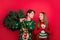 Photo of dreamy couple guy hold x-mas tree girl look hopeful wear ugly pullover isolated red color background