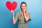 Photo of dreamy excited young lady wear green outfit smiling holding big heart postcard arm cheek isolated blue color