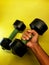 Photo of dumbbell hand muscle exercise equipment with a yellow background