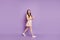 Photo of energetic positive charming cute girl walk hold telephone chatting on purple background