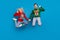 Photo of excited cheerful young couple dressed ugly print sweaters jumping high showing thumbs up isolated blue color