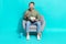 Photo of excited crazy man hold popcorn soda sit armchair watch cinema wear pullover isolated blue color background