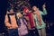 Photo of excited curious four buddies wear windbreakers watching xmas activities together outside urban market park