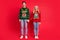Photo of excited dreamy curious couple hold hands empty space wear ugly sweater jeans shoes isolated red color