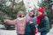 Photo of excited friendly little child wife husband dressed coats choosing x-mas tree outdoors urban forest park