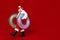 Photo of excited funny man pensioner dressed santa claus costume holding lifebuoys walking empty space isolated red