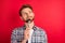 Photo of excited hungry young guy wear checkered shirt licking spoon looking up empty space isolated red color