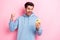 Photo of excited lucky guy dressed blue sweatshirt winning casino modern gadget empty space isolated pink color