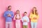 Photo of excited mommy daddy small kids hold cellphone look up copyspace isolated over pastel color background