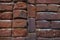 Photo of the exterior surface of an ancient brick wall. Abundant traces of time on the red brick and in the destroyed layer of mor