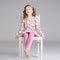 Photo of fashionable sweet little girl posing on the white chair