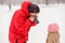 Photo of father dressing his daughter mitten in winter park