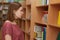 Photo of female youngster poses in bookstore, chooses what to buy for reading, looks attentively at titles, has bobbed haircut,