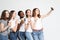 Photo of five multiethnic girls laughing and taking selfie