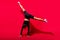 Photo of flexible energetic charming lady stand arms raise legs wear black cropped top isolated red color background