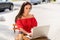 Photo of focused pretty happy young woman sit outside lounge cafe write laptop work outdoors in city center