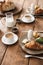 Photo of food on wooden table: croissant, eggs, pastry, milk and cups with coffee