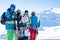 Photo of four athletes wearing helmet and holding snowboards at snow resort .