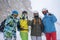 Photo of four happy snowboarders in helmet on background of mountains.