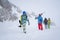 Photo of four sports people with skis and snowboard walking in winter resort