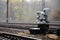 Photo of a fragment of a railway track with a small traffic light in rainy weathe