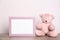 Photo frame and adorable teddy bear on table against light background. Child room elements