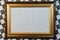 Photo frame with a beautiful gold ornament on a background of chess black and white background.