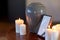 Photo frame, cremation urn and candles on table