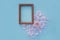 Photo frame heart of light pink petals on a light blue textural background with a flower in the center