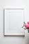 Photo frame mockup with passe-partout hanging on white wall and and bouquet of pink roses with eucalyptus. Empty blank frame and