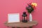 Photo Frame on a wooden and Flowers in jar and Lantern on pink background .