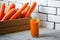 Photo of fresh carrots in a wooden box and a glass of freshly squeezed juice