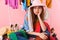 Photo of frightened woman wearing hat sitting near bunch of clothes